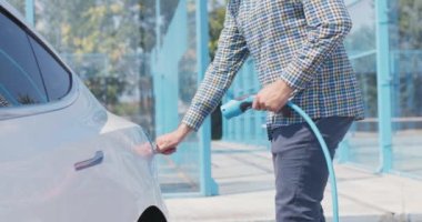 İş kıyafeti giymiş bir adam elektrik kablosunu elektrik prizine takıyor. Uzaklaşıyorum.