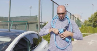 Sakallı ve güneş gözlüklü cesur bir adam elektrik kablosuyla sorun yaşıyor..