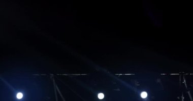 Müzikal performans sırasında sahne ışıklarının yanıp sönen ve dönen ışık huzmeleri