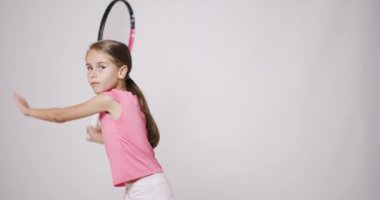 Genç bayan tenis oyuncusu. Pembe spor kıyafetli kız forehand ve backhand hareketi çalışıyor..