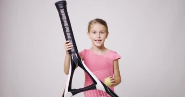 Büyük raket atlayışı yapan genç bayan tenisçi. Elinde topla pembe spor kıyafetli bir kız..