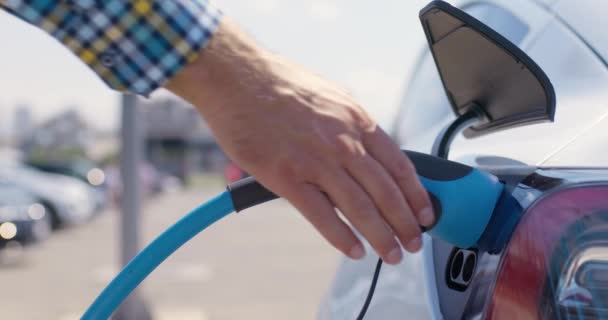 電気自動車の充電ソケットから電源ケーブルを差し込む男性の手 — ストック動画