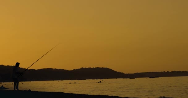 ロッドで人々の水泳や漁師のシルエット ビーチでの夕日 — ストック動画