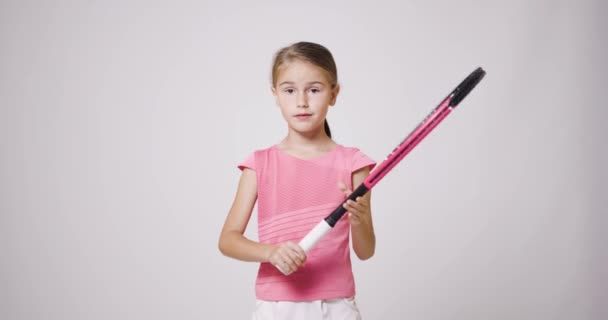 年轻的女网球选手拿着球拍 穿着粉色运动服的女孩看着镜头 — 图库视频影像