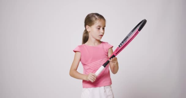 年轻的女网球选手 穿着粉色运动服的女孩看着球拍 — 图库视频影像
