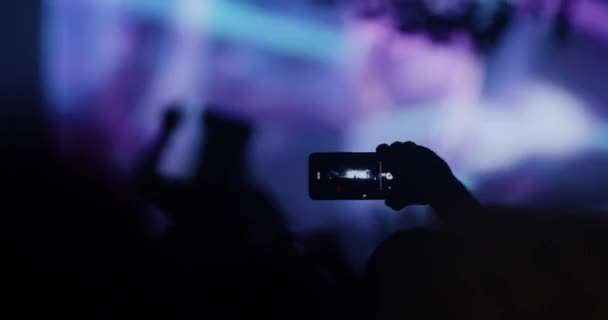 人群中的人物形象 手举起舞 手持智能手机 闪光和失焦阶段 — 图库视频影像