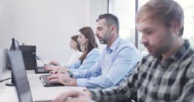 Ofisteki insanlar dizüstü bilgisayarlar ve bilgisayarlar üzerinde çalışıyorlar. İş arkadaşları takımı. Saha videosunun derinliği. Kamera hareketini ileri al.