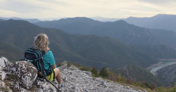 Turistka Sedící Skalnatém Terénu Horách Ukazuje Výhled Nebo Říční Jezero — Stock video
