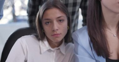 İşçilik ekibi bilgisayar ekranının önünde bir ofiste çalışıyor. Kameraya bakan bayan meslektaşına odaklan. Ciddi ifade.