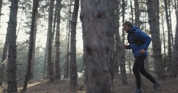 穿着冬季运动服的小径跑步者 在森林小径上奔跑的人阳光在树间闪耀 以120 Fps的速度记录 — 图库视频影像