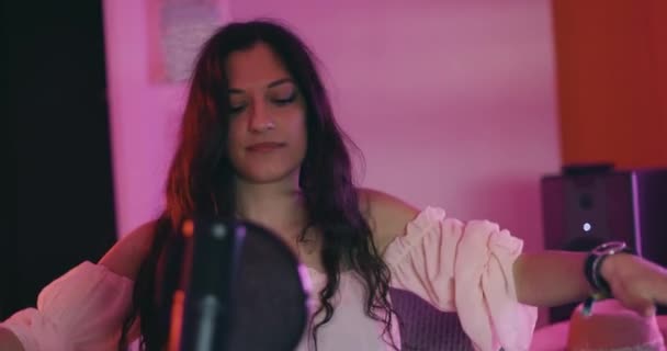 マイクの前で踊る女の子 オーディオ録音機器を備えたスタジオでの女性音楽パフォーマー 歌を作る カラフルなライト — ストック動画