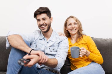 Birbirine aşık çiftler bir kanepede oturup televizyon seyrederler. Kahve ve uzaktan kumanda elinde