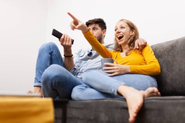 Birbirine aşık çiftler bir kanepede oturup televizyon seyrederler. Kahve ve uzaktan kumanda elinde