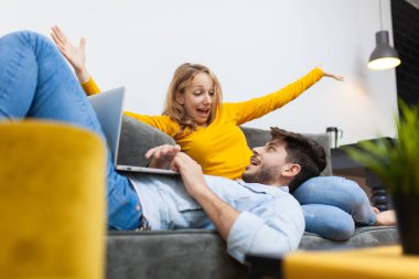 Lovery çifti evdeki kanepede. Kız arkadaşının kucağında dizüstü bilgisayarı olan bir çocuk. Şaşırtıcı ifadeler ve jestler.