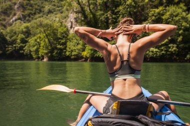 Genç aktif kız dağlarda bir nehirde kano gezintisinin tadını çıkarıyor.