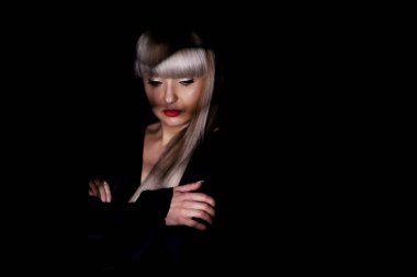 Sarışın, püsküllü, siyah, şık elbiseli, gölgelerin altında poz veren güzel bir kız.