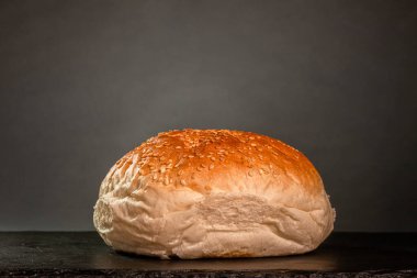 burger bun with sesame seeds on gray background.