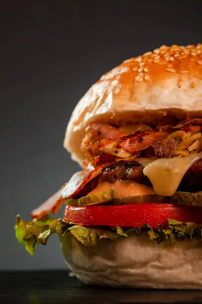 Burger with bacon onions tomatoes cucumber lettuce and souces. Abstract fast food photo.