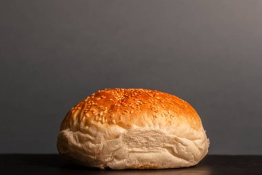 burger bun with sesame seeds on gray background.