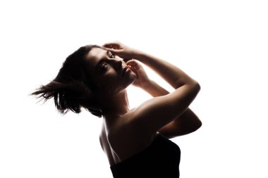 Kısa saçlı ve elleri havada bir kızın yarı siluet portresi. Beyaz arkaplan karşısında izole