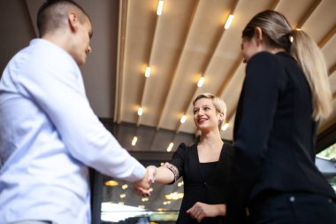 Üç genç iş adamı sohbet ediyor ve el sıkışıyor. Çalışma saatleri dışında modern bir kafede beyin fırtınası yapan başarılı bir çalışma ekibi..