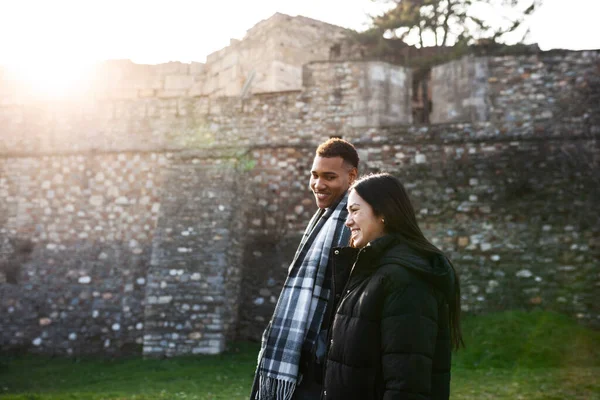 男人和女人走在一座古老的石墙前 恋爱中的多种族夫妇 — 图库照片
