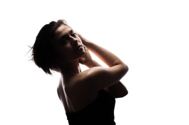 Kısa saçlı ve elleri havada bir kızın yarı siluet portresi. Beyaz arkaplan karşısında izole