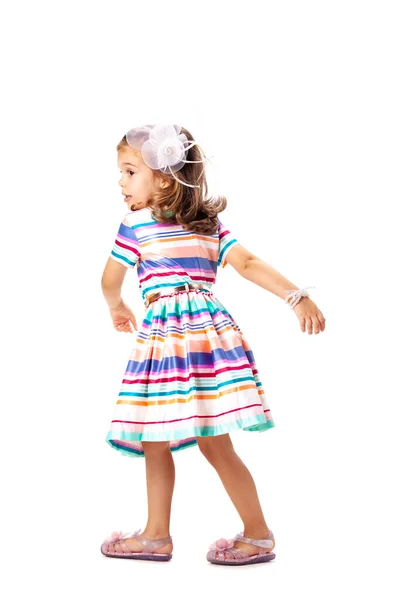 一个快乐的小女孩穿着五颜六色的衣服站在演播室里 孤零零地躺在白色的墙上 — 图库照片
