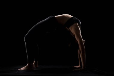 Siyah arka planda yoga pozu veren beyaz bir kız. yan aydınlatma silueti.