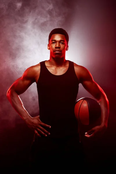 バスケットボール選手側は煙を背景にボールを保持赤い色で点灯 深刻な集中アフリカ系アメリカ人男性 — ストック写真