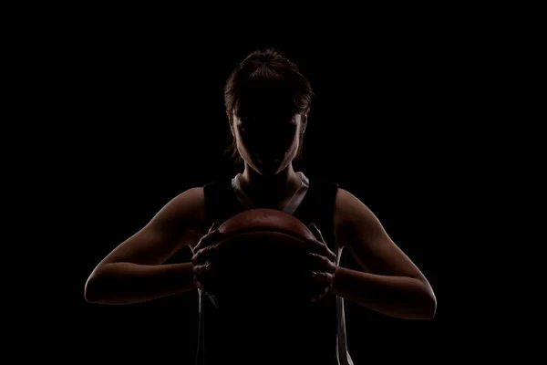 女子バスケットボール選手 美しい女の子がボールを持っている サイドライトハーフシルエットスタジオポートレート黒の背景 — ストック写真