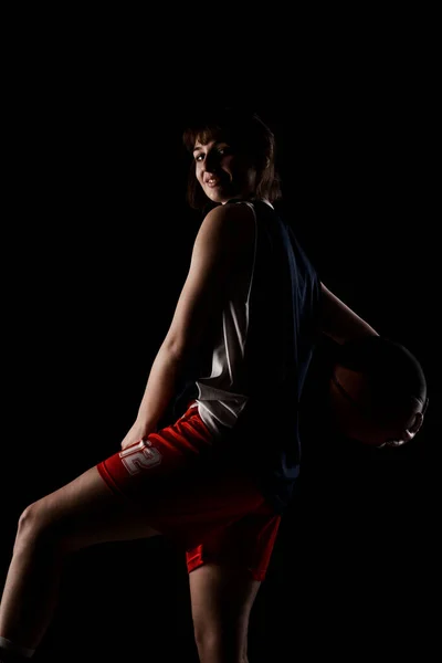 女子バスケットボール選手 美しい女の子がボールを持っている サイドライトハーフシルエットスタジオポートレート黒の背景 — ストック写真