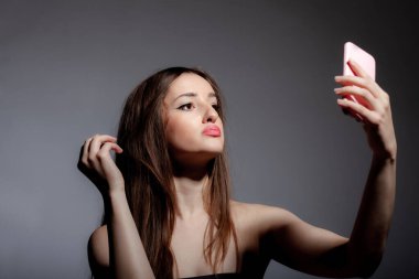 Telefona bakan güzel bir kız. Gri arka planda fotoğraf stüdyosunun portresini çekiyor..