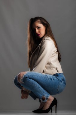 Uzun saçlı, kot pantolon ve ceket giyen güzel bir kızın vücut hatları.