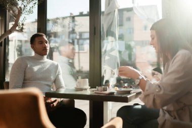 Friends in a restaurant talking smiling and drinking tea. Business colleagues having a meeting after work or during coffee break at a cafe bar.