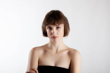 Beyaz arka planda, kısa saçlı güzel esmer bir kızın stüdyo portresi..