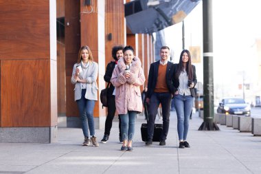 Bir grup insan sokakta güven içinde yürüyor. İş adamları ve iş kadınları birlikte seyahat ediyorlar..
