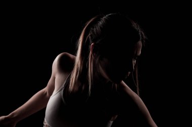 Güzel beyaz kız gölgede yoga pozu veriyor. yan ışıklandırılmış fotoğraf siyah arkaplanda.