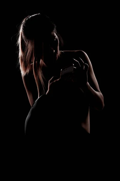 美丽的高加索女孩在阴影中手持电话 在黑色背景上的侧光照片 — 图库照片