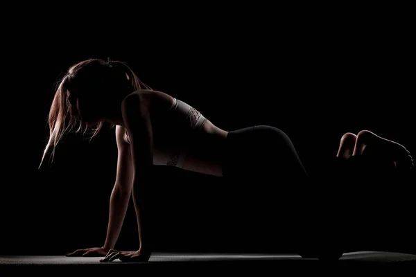 美丽的高加索女孩在阴影中摆出瑜伽的姿势 在黑色背景上的侧光照片 — 图库照片