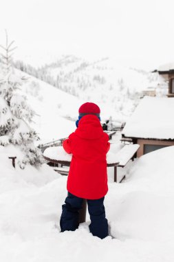 Little boy on a cold winter day in the mountains. Playing with snow. Throwing snow balls.