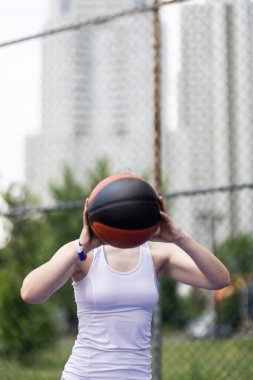 Basketbol oynayan kız. Top atan oyuncu. Kentsel çevrede açık hava spor sahası.