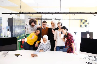 Modern ofis işyerinde selfie çeken başarılı çok ırklı iş arkadaşları takımı. Gülümsüyor ve kameraya el sallıyor..