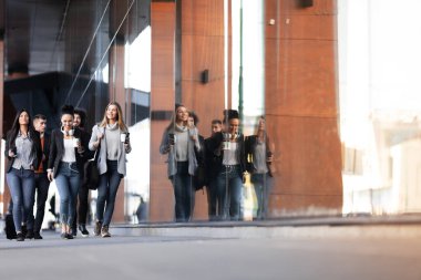 Bir grup insan sokakta güven içinde yürüyor. İş adamları ve iş kadınları birlikte seyahat ediyorlar..