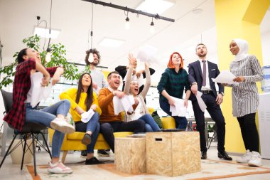 Modern ofis işyerindeki çok ırklı başarılı iş arkadaşlarının oluşturduğu takım başarıyı kutlamak için kağıt fırlatıyor. Çeşitlilik mutluluk kavramı.