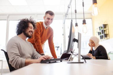 İş adamları bilgisayarın önünde sohbet ediyorlar. Modern çok ırklı ofis alanı. 