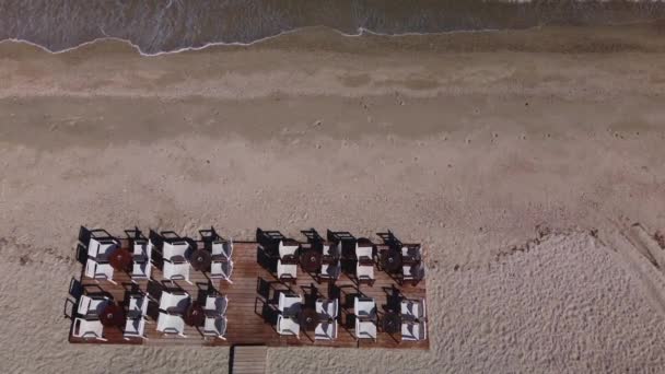 靠近大海的木制平台上的咖啡店或餐馆的椅子和桌子 空中视频空旷的海滩景观下来 — 图库视频影像