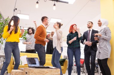 Modern ofis işyerinde dans eden ve başarıyı kutlayan başarılı çok ırklı iş arkadaşları takımı. Çeşitlilik mutluluk kavramı.
