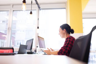 Modern bir ofis alanında masaüstü bilgisayarı üzerinde çalışan sıradan bir iş kadını..