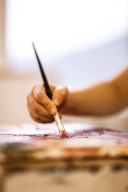 Sanatsal bir tabloda fırça kullanan bir el. Sanat yaratan kadın sanatçı..